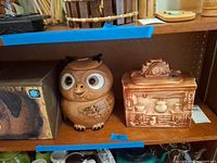 Shelf view showing McCoy owl cookie jar with lid and stove-relief USA canister