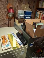 overall view of filing cabinet top with hole punch, rulers, floppy disks, CD jewel cases in box
