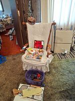 Overall lot on chair: wind chime hanging, open box with origami, damaged coin bank, tote on floor