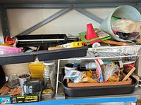 Overview of shelves with caulking gun, rollers, pail, tray, tubes, brushes