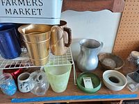 Group view showing multiple metal pitchers, enamel tub, planters and flower frogs