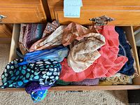 Open drawer showing multiple scarves of various patterns and fabrics