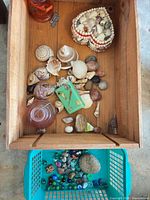 Wooden crate with shell trinket box, assorted seashells, stones; blue basket with marbles and rocks