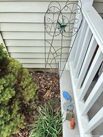 Trellis positioned by porch with ceramics at base