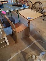 Overall view of vintage metal and wood school desk chair showing seat, backrest, metal base and attached writing tablet