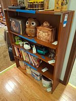 Front view of wood shelving unit showing five shelves and pegboard back