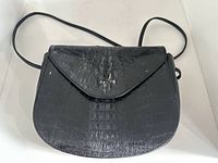 Front view of black crocodile leather purse showing flap and strap