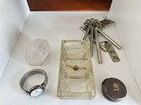 Group of five items: wristwatch, quartz crystal, glass ashtray, metal wind chime, metal pill box