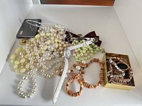 Overall view of assorted necklaces, watches, bracelet and Guess accessory on white surface