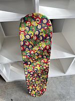 Full view of skateboard deck showing multicolour smiley face graphic