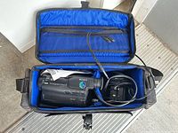 Camcorder in open padded case with adapter and cables visible