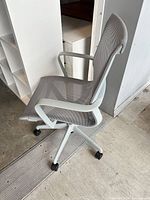 Side view of gray mesh Uline office chair showing armrest, seat, back, base and casters