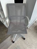 Top view of gray mesh swivel office chair with armrests and casters