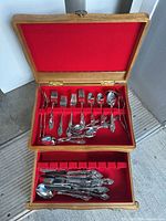 Overall view: open wooden chest showing two tiers of silver-tone flatware