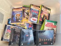 Stack of Fighting Fantasy paperback books and Blizzard PC CD-ROM games in bin