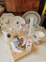 Full lot view showing plates, pitchers, sugar bowl, vase, coasters on wood board