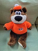 Front view of brown plush A&W bear wearing orange sweater and hat