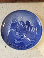 Front view of blue and white 1971 Christmas plate showing family at piano scene