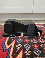 Front view of black carved wood dog doorstop on rug