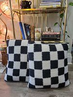 Front view of both black and white checkerboard sherpa pillows