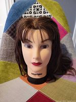 Front view of mannequin head on patchwork fabric backdrop