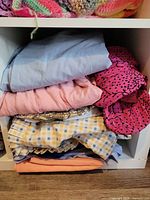 Stack of assorted folded sheets and fabrics showing colours and patterns