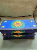 Closed blue wooden box with sunflower and stars painted on lid