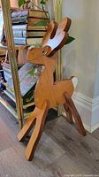 Full view of wooden reindeer standing beside shelf