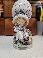 Front view of Holly Hobbie ceramic figurine showing bonnet, dress, base