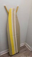Front view of ironing board standing upright with striped cover