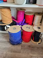 Multiple large ribbon spools on shelf and floor showing colour variety and material