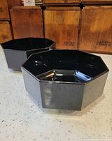 Two black octagonal bowls angled side view