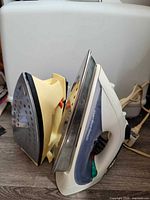 Both steam irons standing on soleplates showing bodies and cords