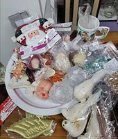 Serving bowl filled with assorted ornaments, doll parts and mug visible