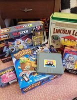 Group shot showing Telepods box, Lincoln Logs tin, Don't Rock the Boat box, Garfield puzzle box, Battleship part, Crystal puzzle