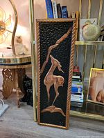 Full view of vertical copper relief wall panel leaning against shelf