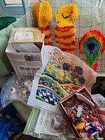 Overview of lot showing latch hook pieces, needlepoint canvas, floss boxes