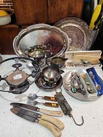 Group shot of all items including trays, hollowware, chafing stand, cutlery and knives