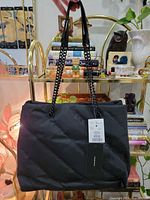 Front view of black quilted Nicole Miller tote with tags visible
