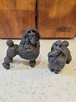 Two ceramic poodle figurines side by side