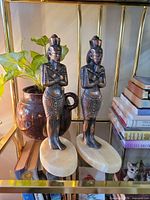 Front view of both brass Egyptian statues on marble bases