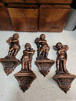 Front view of all four bronze/copper cherub corbels