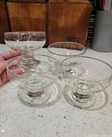 four clear glass footed dessert dishes on countertop