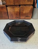 Stack of six black octagonal plates showing edges