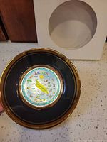 Top view of black and gold Aruba souvenir plate with storage box