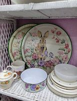 Shelf with rabbit plates, enamel bowl, sugar bowl, mug, stack of plates