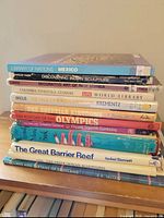 Entire stack of eleven hardcover coffee-table books showing spines