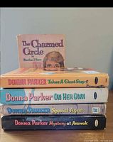 Stack of four Donna Parker hardcovers with spines visible and The Charmed Circle standing at back