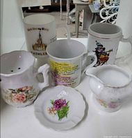 Overall lot showing three mugs, two floral creamers and trinket dish