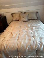 Bed made up displaying comforter, shams and cushion